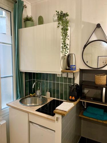 - une petite cuisine avec un évier et un miroir dans l'établissement Le Cosy, charmant studio centre ville, à Rennes