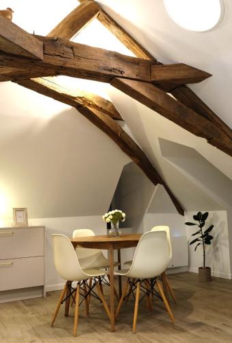 une salle à manger avec une table en bois et des chaises blanches dans l'établissement La Citadelle Endormie à Ombrée d'Anjou, à Pouancé