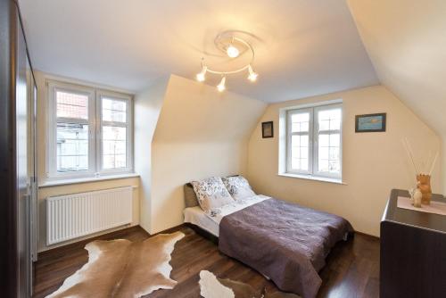 a bedroom with a bed and two windows at Gdańskie Apartamenty - Apartamenty na Sw Ducha - Gdańskie Poddasza z jacuzzi i De Luxe in Gdańsk