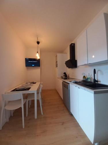- une petite cuisine avec une table et un comptoir blanc dans l'établissement Le 29 , 4pers, 2 lits, climatisation et wif, à Agen
