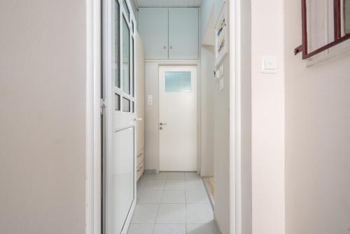 a hallway with a white door and a white tile floor at In the center of Messolonghi in Mesolongion