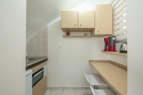 a kitchen with white walls and wooden cabinets at In the center of Messolonghi in Mesolongion