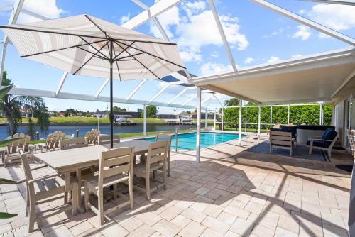 a patio with a table and an umbrella and a pool at Cozy Cape Cottage Gulf Access in Waterway Estates