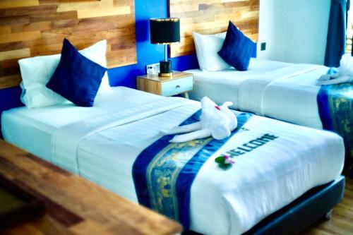 a hotel room with two beds with a stuffed animal on them at Three Trees Samui Resort - Sarocha Villa in Lamai