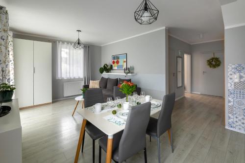 a dining room and living room with a white table and chairs at Apartamenty Wczasowa - z widokiem na góry, parkingiem, rowerownią in Kudowa-Zdrój
