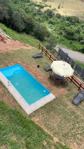 - une vue sur la piscine avec une table et un parasol dans l'établissement Chacrinha pousada e restaurante Chalé Seriema, à Caldas Novas