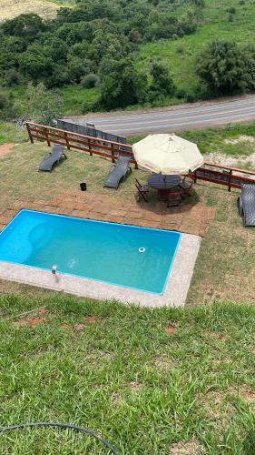 une piscine avec une table et un parasol dans l'établissement Chacrinha pousada e restaurante Chalé Seriema, à Caldas Novas