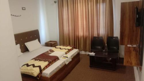 a bedroom with a bed and two chairs and a window at Book inn apartment in Srinagar