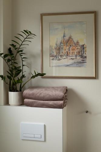 a painting on a wall with a plant on top of a refrigerator at Apartamenty Wczasowa - z widokiem na góry, parkingiem, rowerownią in Kudowa-Zdrój