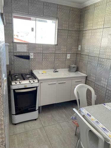 a small kitchen with a stove and a sink at Suítes Sol e Mar - Arraial do Cabo na Praia dos Anjos in Arraial do Cabo