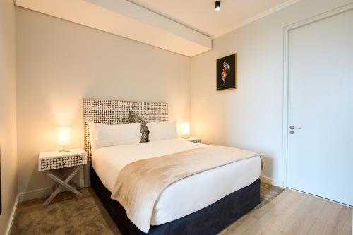 a bedroom with a large white bed with two lamps at 8's at Ellipse Waterfall in Midrand