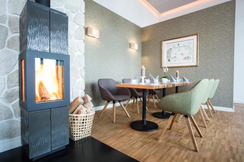 a dining room with a fireplace and a table and chairs at Hotel Strand26 in Nienhagen