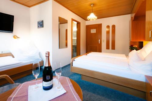 a hotel room with two beds and a bottle of wine on a table at Hotel Grünwinkel in Oberharmersbach
