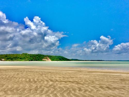 a beach with sand and a blue sky and clouds at Pousada Bella Maré in Goiana