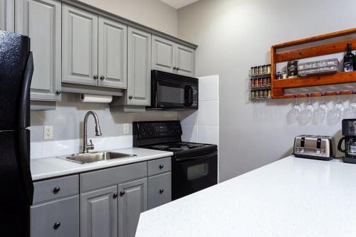 a kitchen with white cabinets and a black refrigerator at BigWhite Ski In-Out Chalet w Priv HotTub & Garage in Big White