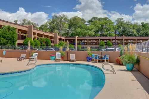 a pool in front of a hotel with chairs and tables at El Sendero Inn, an Ascend Collection Hotel in Santa Fe