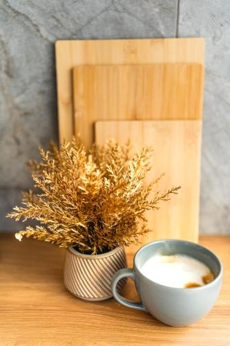 a cup of coffee and a vase with a plant at Apartamenty Podtatrzański in Leśnica