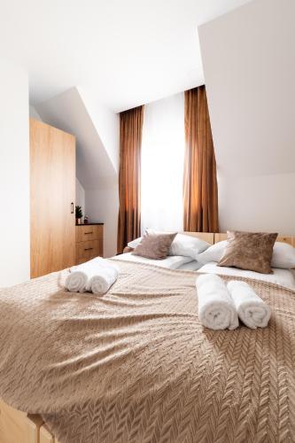 a bedroom with a large bed with towels on it at Apartamenty Podtatrzański in Leśnica