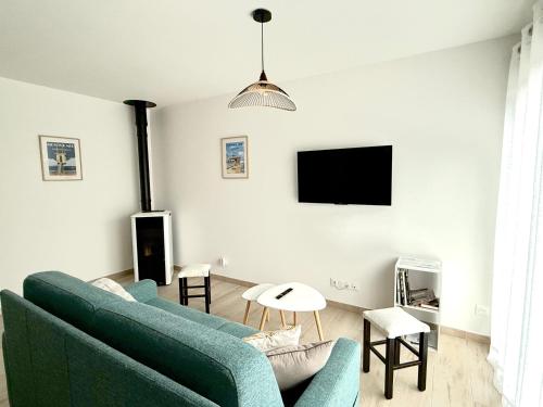 a living room with a blue couch and a tv at Maison à 100m de la mer in Hermanville-sur-Mer