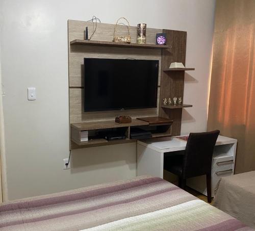 Una habitación con un escritorio con televisión y una cama. en Casa de 2 Plantas, en São Gabriel