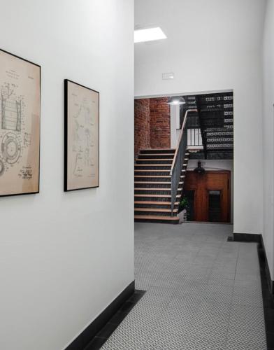 a hallway with two pictures on a wall and stairs at Unique apartment in Ratibor in Racibórz