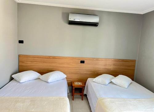 a bedroom with two beds and a tv on the wall at Santa Rita Pousada in Guarujá