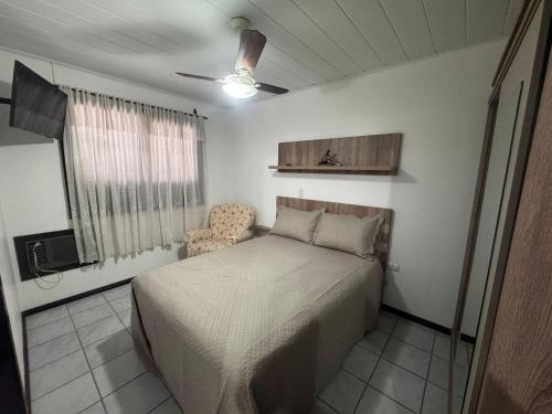 a bedroom with a bed and a chair in it at A55 - Casa centro de Bombinhas in Bombinhas