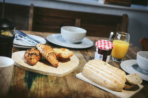 a wooden table topped with bread and croissants and orange juice at Llanfair Hall, Dog Friendly, Cinema, Games Room, Hot Tub in Llanfairpwllgwyngyll