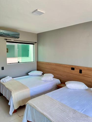 a room with two beds and a window at Santa Rita Pousada in Guarujá
