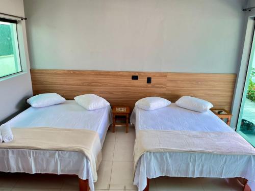 a room with two beds and a window at Santa Rita Pousada in Guarujá