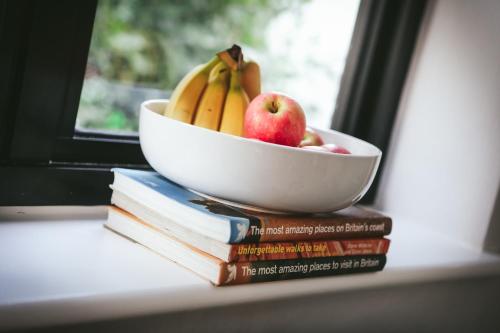 a bowl of bananas and apples on a stack of books at Llanfair Hall, Dog Friendly, Cinema, Games Room, Hot Tub in Llanfairpwllgwyngyll