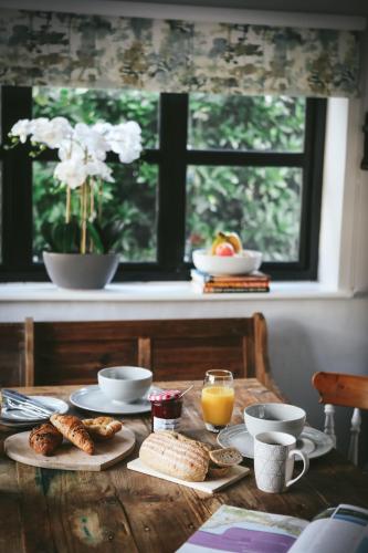 a wooden table with breakfast foods and a window at Llanfair Hall, Dog Friendly, Cinema, Games Room, Hot Tub in Llanfairpwllgwyngyll