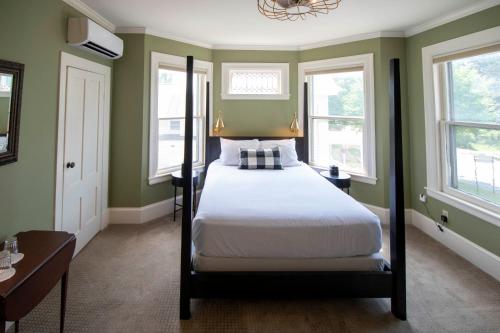 a bedroom with a bed and two windows at Swift House Inn in Middlebury