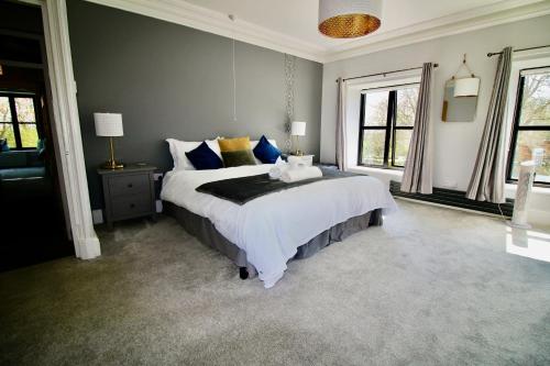 a bedroom with a large bed with blue and yellow pillows at Llanfair Hall, Dog Friendly, Cinema, Games Room, Hot Tub in Llanfairpwllgwyngyll
