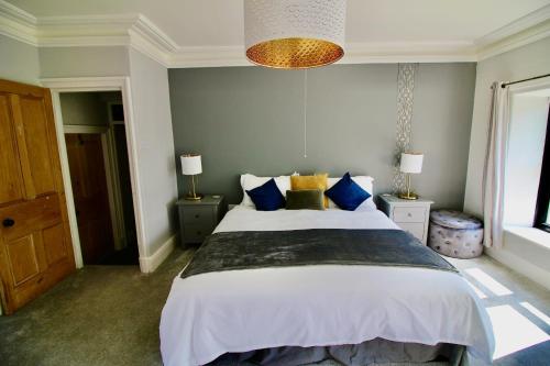a bedroom with a large bed with blue and yellow pillows at Llanfair Hall, Dog Friendly, Cinema, Games Room, Hot Tub in Llanfairpwllgwyngyll