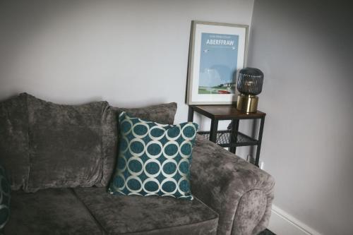 a brown couch with a blue pillow and a table at Llanfair Hall, Dog Friendly, Cinema, Games Room, Hot Tub in Llanfairpwllgwyngyll