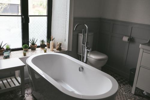 a white bath tub in a bathroom with a toilet at Llanfair Hall, Dog Friendly, Cinema, Games Room, Hot Tub in Llanfairpwllgwyngyll