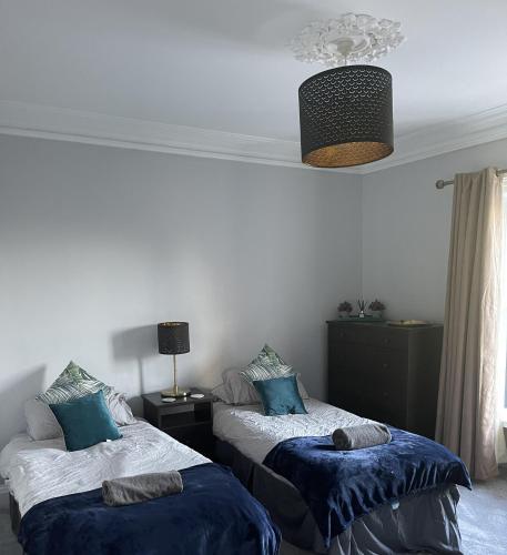 a bedroom with two beds with blue pillows at Llanfair Hall, Dog Friendly, Cinema, Games Room, Hot Tub in Llanfairpwllgwyngyll