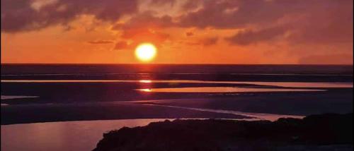 a sunset over the ocean with the sun setting at Llanfair Hall, Dog Friendly, Cinema, Games Room, Hot Tub in Llanfairpwllgwyngyll