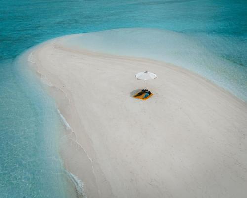 an island with an umbrella on a beach at Island Serenity in Dhiffushi