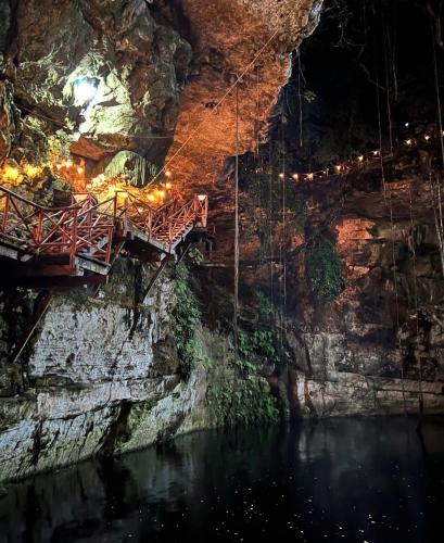 a bridge in a cave with water and lights at Hotel Boutique Cenote Secreto Maya in Yaxché