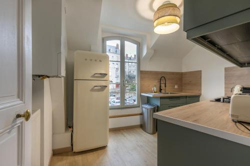 une cuisine avec un réfrigérateur blanc et une fenêtre dans l'établissement Le Nid de Saint Honoré - sur les toits de Blois, à Blois