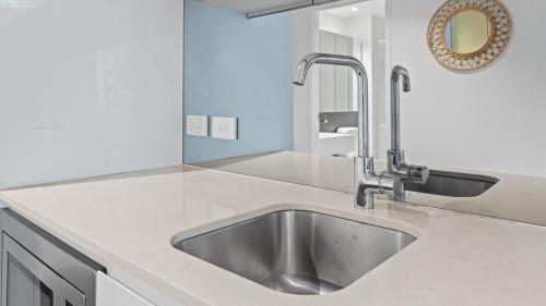 una cucina con lavandino in acciaio inossidabile e specchio di The Downtown Nest a Melbourne