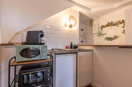 une petite cuisine avec un micro-ondes et une cuisinière dans l'établissement ☆ Sur les toits de Blois ☆ T2 avec vue Château, à Blois