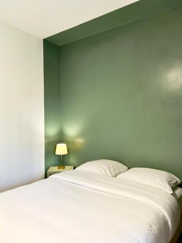 a bedroom with a white bed and a green wall at Studio avec jardin & piscine - vue forêt in Rémiré