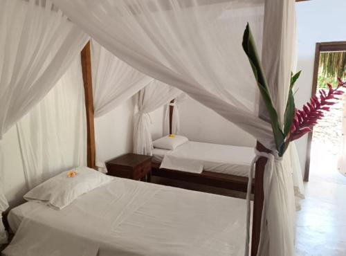 two beds in a room with white curtains at Sierra Sagrada in Santa Marta