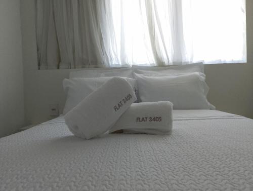a bed with two white pillows and a large window at Beach Class Convention - Flats em Boa Viagem por Yolo in Recife