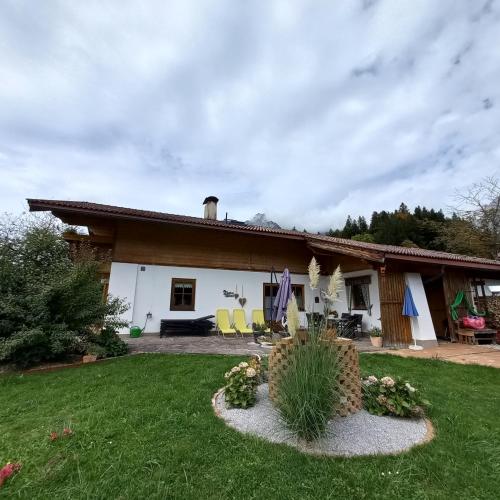 a white house with yellow chairs in a yard at Chalet Glücklich sein... in Ellmau