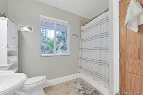Un baño con inodoro, lavabo y ventana. en Gorgeous 4-bedroom beach space, en Hollywood