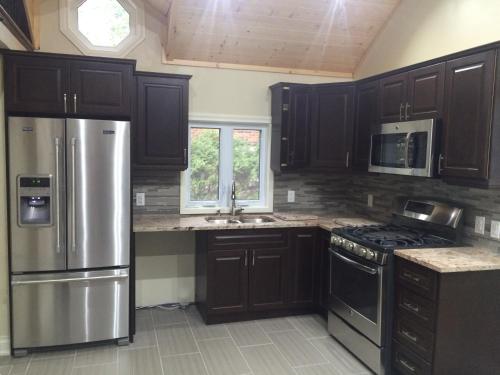 une cuisine avec des armoires en bois et un réfrigérateur en acier inoxydable dans l'établissement Victoria Harbour Cottages, à Victoria Harbour